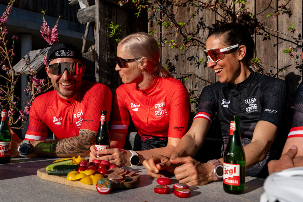 Drie wielrenners met teamshirts in de pauze met hapjes en drankjes tijdens de racefietstocht
