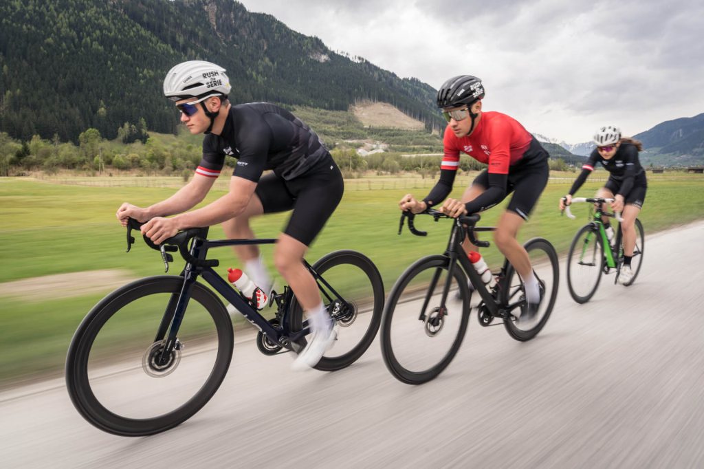 Drie racefietsers in een groep rijden een langeafstandsrace op de racefiets in de Alpen bij Saalfelden